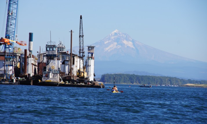 Columbia River near Vancouver, Washington showing water, mountain, and industry with a small kayaker in the background.
